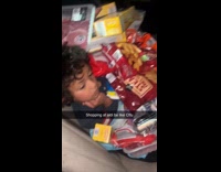 Pile of groceries over sleepy boy in car