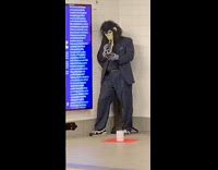 Gorilla in business suit plays the trombone trumpet in subway station