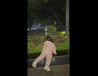 Baby girl looks over planter ledge 