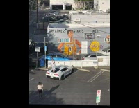 Man stands on the car in front of Kobe Mural