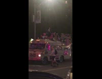 Man sing and dance at top of the mini bus along street 