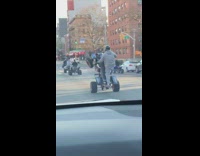 Group of people ride ATVs down street