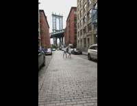 Couple dancing recording camera down street new york bridge 