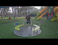 Teen standing inclined on playground spinner