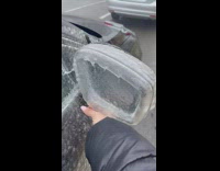 Girl removes frozen mirror ice on car 