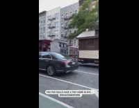 Multiple tiny homes on a trailer bed being towed by a big rig truck 