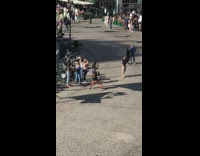 Girl orange pants takes picture of friend on roundabout street