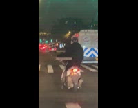 Man driving scooter with one hand and holding pizza