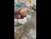 Cutting orange with knife then squeezing all of the juice out into sink