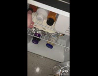 Guy opens mini fridge and pulls out white bottle  