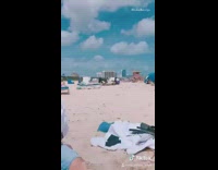 Guy sits alone in the sand with towel over head at the beach, all by myself song