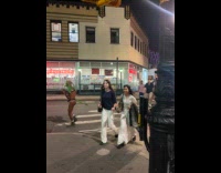 Man in thong with mask, wings and tail dancing on crosswalk