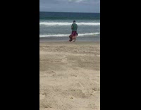 Woman in bikini attempts handstand on the beach 