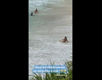 woman lays on sand wave crashes face