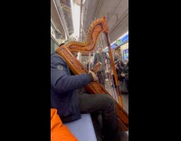 Man play huge harp inside subway train