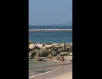 Woman brown hat white bikini sit rock