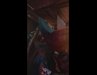 Woman in blue gem bra outfit dances with giant blue fan at the bar