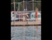 Woman in red bikini poses at the net at the docks