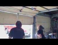 Girls drink beer taped to garage door