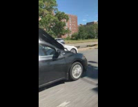 Black car driving on freeway with hood open