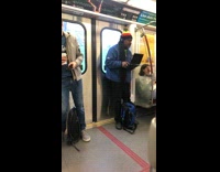 Man in rasta beanie and plays reggae music on his laptop on the subway