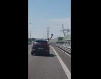 Guy in back seat sticks head out of moving car window and chugs out of beer pong