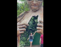 Woman black top raises hand in front of the Tulum Statue