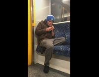 Guy wearing blue beanie smokes on subway 