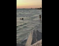 woman lays on beach facing ocean waves