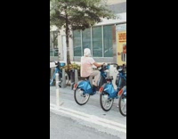 Pink shirt grandma pedals locked rental bicycle