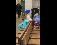Person in alligator mask waiting for train on bench