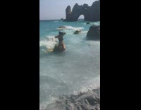 Woman black bikini photo shoot rock waves beach side