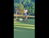 Man golfs while another man lie down and films it