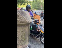 Man sprays water on cat wearing sunglasses