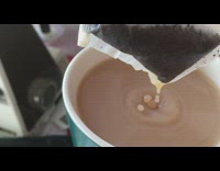 Water drops from the tea bag to the cup