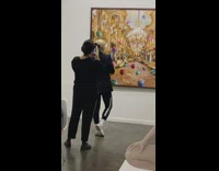 Woman in a suit faces the painting in the museum