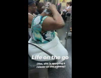 Woman in blue green floral shirt applies hair relaxer on subway train