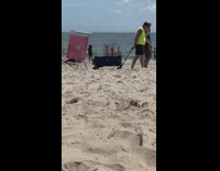 Old guy pulls a cage with bird in side on sand 