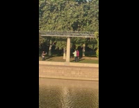 Two men tiktok dance near the lake at the park