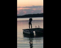 Guy dancing on platform float in the middle of lake