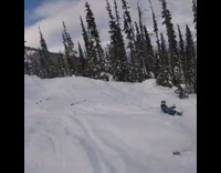 Skier jumps off mountain side, flies off skis and front flips down slope