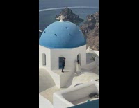 Groom help bride climb roof wedding Santorini