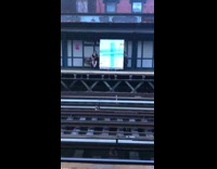 Person rolls giant mirror wrapped in tape and foam down train station