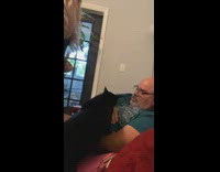 Cat meows at woman hitting man on couch 