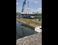 Crane moves black white submarine boat water 