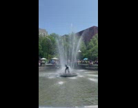 man in wetsuit stand in the middle of a fountain