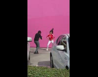Red jacket girl dances by pink wall 