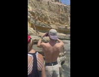 Woman black shorts do handstand on rock