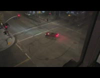 Red convertible car donuts middle of intersection 