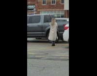 Woman in brown coat poses and vlogs at the parking lot